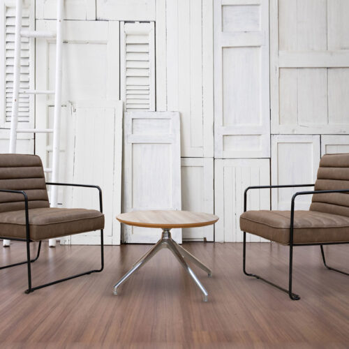 Two industrial lounge chairs in brown faux leather, and a small round coffee table