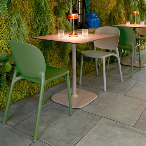 Two plastic cafe and dining chairs in green with a small square table