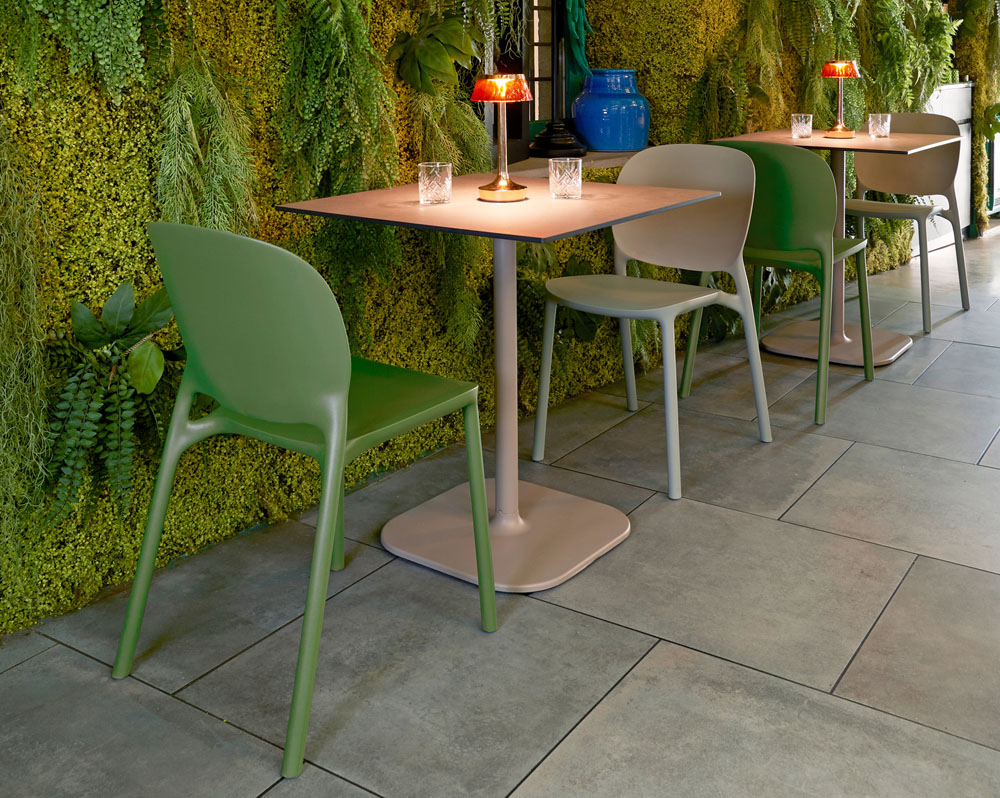 Two plastic cafe and dining chairs in green with a small square table