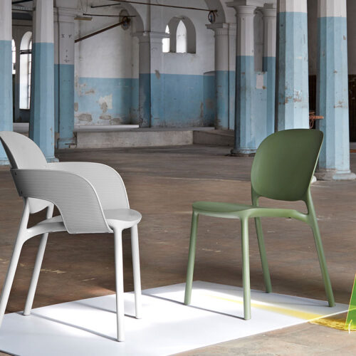 A white plastic reception chair and a green plastic reception chair in a reception