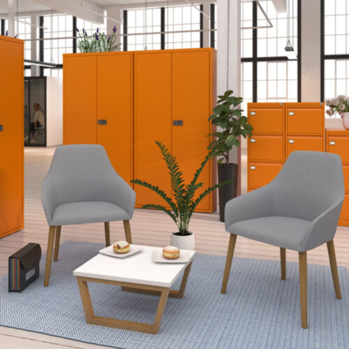 Waiting room chairs in grey fabric and wooden legs, and a small white coffee table, in a waiting area