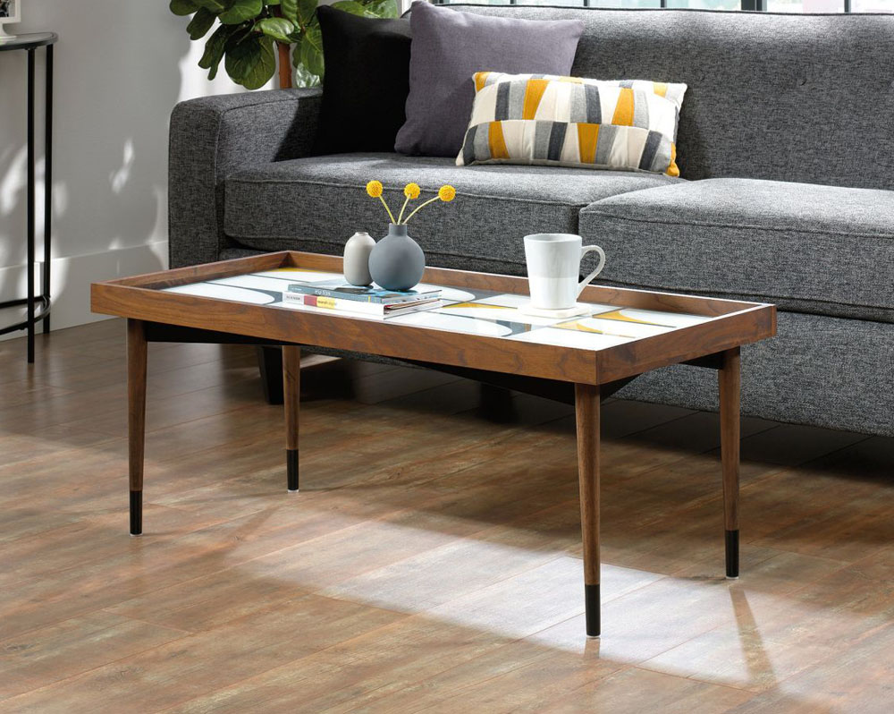 A rectangular coffee table with screen printed top in front of a grey sofa