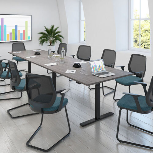 An electric sit stand meeting table surrounded by mesh back meeting chairs